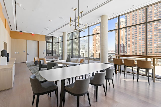 dining room featuring a city view, wood finished floors, a chandelier, plenty of natural light, and expansive windows