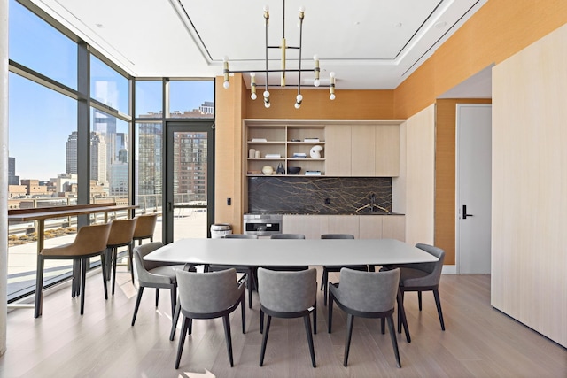 dining room featuring light wood-style floors, expansive windows, and a skyline view