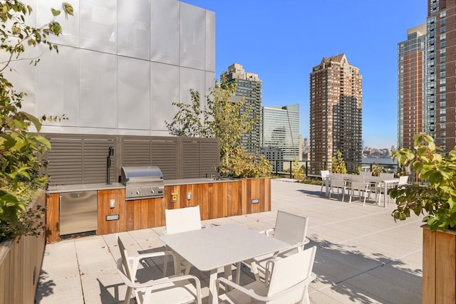 view of patio with outdoor dining space, a grill, a view of skyline, an outdoor kitchen, and a sink