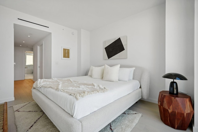 bedroom featuring light wood-style flooring and connected bathroom