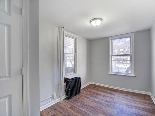 spare room featuring radiator and dark wood-type flooring