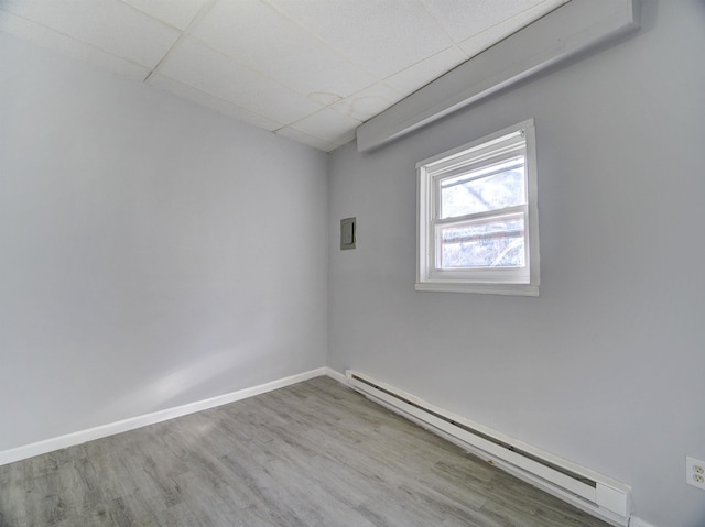 unfurnished room with a baseboard heating unit, a paneled ceiling, and light hardwood / wood-style floors