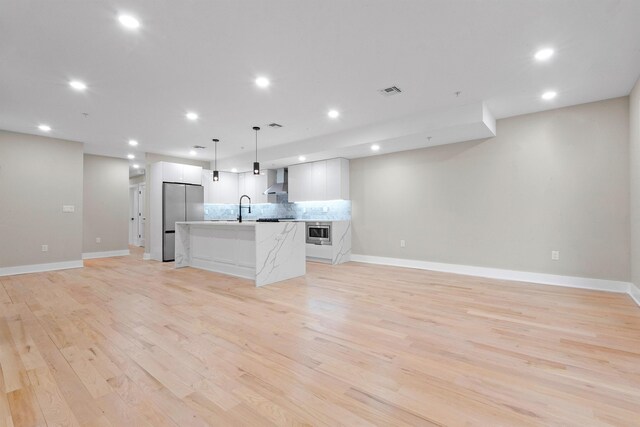 211 Summit Ave Unit 2, Jersey City, NJ 07304 - kitchen featuring stainless steel appliances, wall chimney range hood, open floor plan, a center island with sink, and recessed lighting