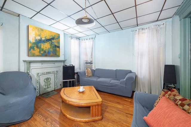 living area featuring a fireplace with flush hearth, wood finished floors, and a paneled ceiling