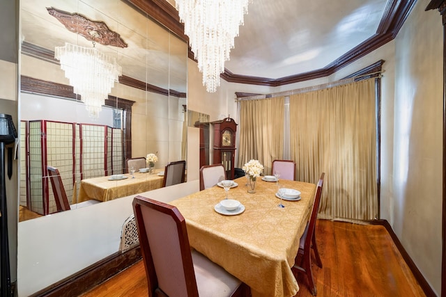 dining room with an inviting chandelier, ornamental molding, wood finished floors, and baseboards