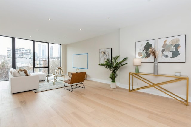 living room with recessed lighting, expansive windows, baseboards, and light wood finished floors