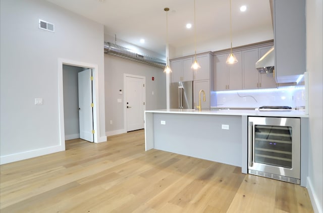 kitchen featuring wall chimney exhaust hood, wine cooler, backsplash, decorative light fixtures, and gray cabinets