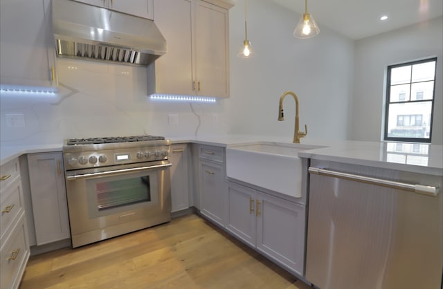 kitchen featuring stainless steel range, sink, light hardwood / wood-style floors, decorative light fixtures, and gray cabinets