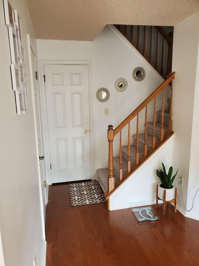 entrance foyer featuring stairway, a textured ceiling, and wood finished floors