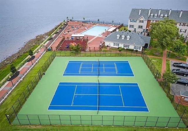 view of sport court with a water view and fence