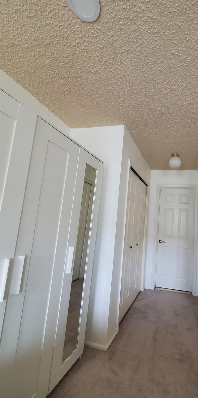 corridor with carpet and a textured ceiling