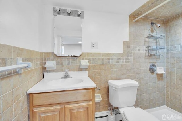 bathroom with a tile shower, vanity, tile walls, and toilet