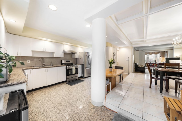kitchen with stainless steel appliances, a sink, under cabinet range hood, light stone countertops, and white cabinets