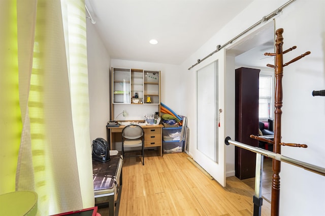 home office featuring wood finished floors, a barn door, and recessed lighting