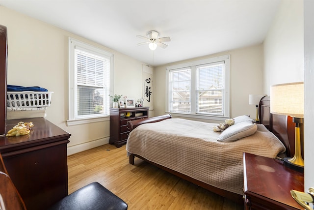bedroom with light wood-style flooring, baseboards, and a ceiling fan