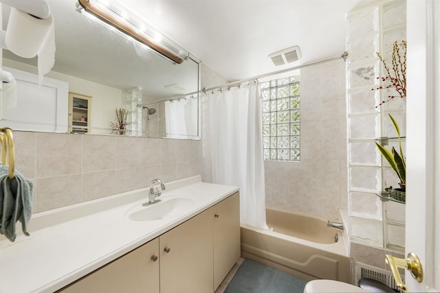full bath with shower / bath combo with shower curtain, vanity, and tile walls