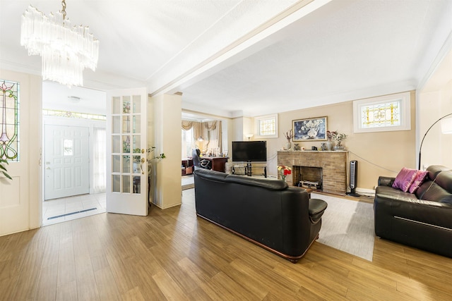 living room with wood finished floors, a chandelier, and a brick fireplace