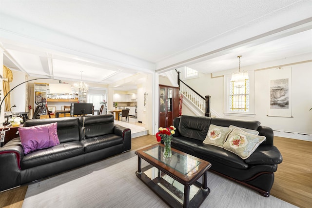 living room with a chandelier, beamed ceiling, stairs, a baseboard radiator, and wood finished floors