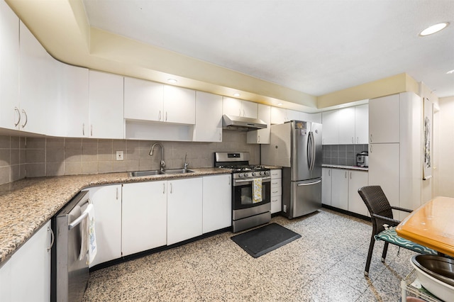 kitchen featuring appliances with stainless steel finishes, under cabinet range hood, a sink, decorative backsplash, and recessed lighting