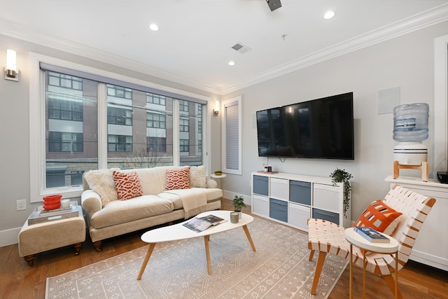 living area with baseboards, visible vents, ornamental molding, and wood finished floors