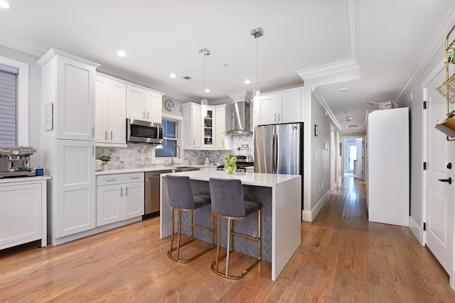 kitchen featuring appliances with stainless steel finishes, light countertops, wall chimney exhaust hood, and white cabinetry