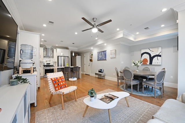 living room with ornamental molding, light wood-type flooring, visible vents, and recessed lighting