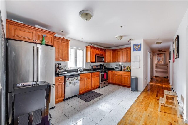 55 71st St, Guttenberg, NJ 07093 - kitchen with stainless steel appliances, a sink, dark countertops, and brown cabinets
