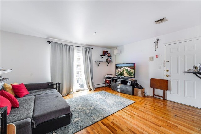 55 71st St, Guttenberg, NJ 07093 - living room with wood finished floors and a baseboard heating unit
