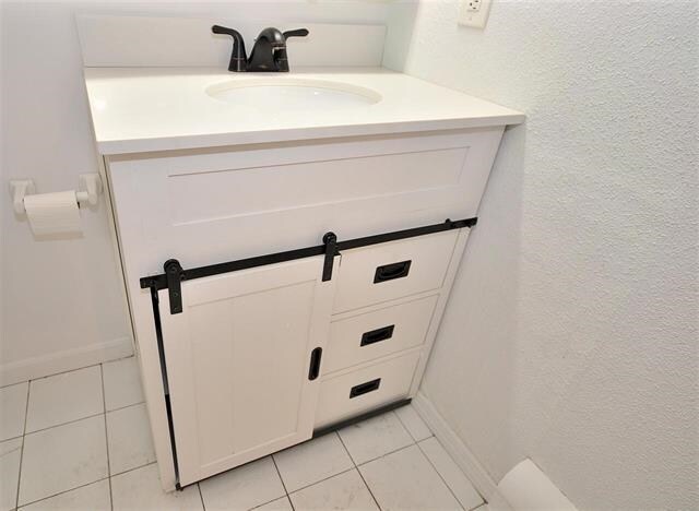 55 71st St, Guttenberg, NJ 07093 - detailed view of vanity, a textured wall, and baseboards