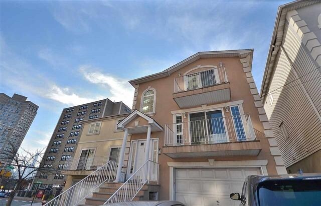 55 71st St, Guttenberg, NJ 07093 - view of front of home featuring stucco siding, a balcony, and a garage