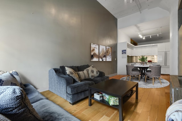 living room featuring a towering ceiling, track lighting, and light hardwood / wood-style floors