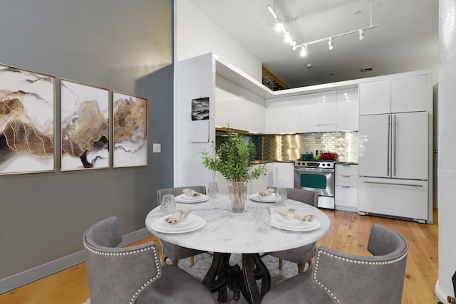 dining room with rail lighting and light hardwood / wood-style flooring