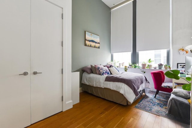 bedroom featuring a towering ceiling and light hardwood / wood-style flooring