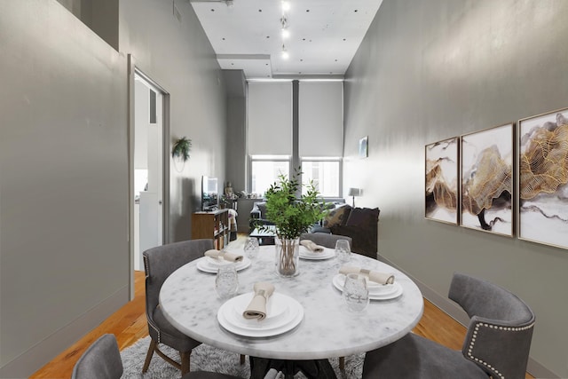 dining room featuring light hardwood / wood-style flooring and a high ceiling