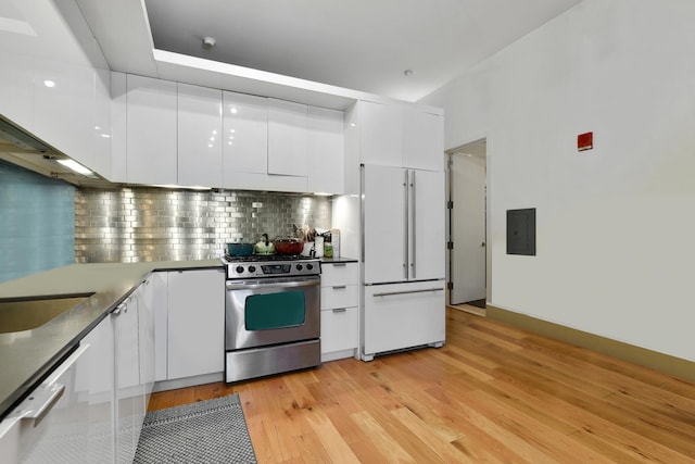 kitchen featuring stainless steel gas stove, paneled built in fridge, dishwasher, and white cabinets