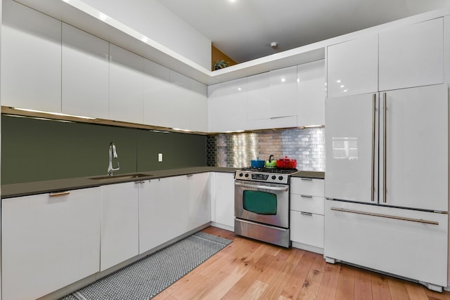 kitchen featuring stainless steel gas stove, sink, paneled built in fridge, and white cabinets