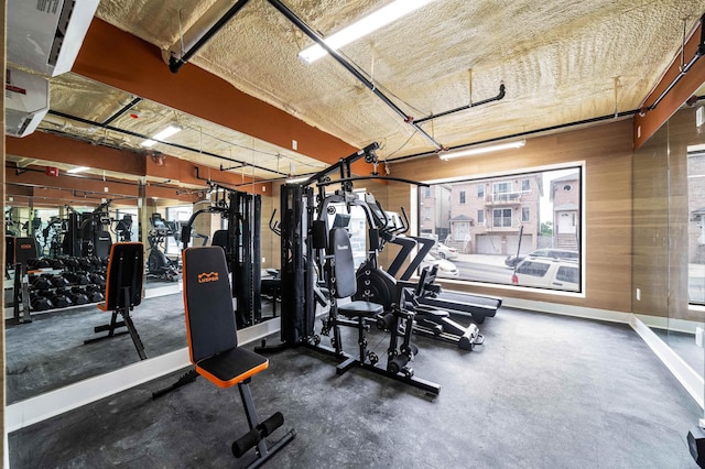 gym featuring a healthy amount of sunlight and wooden walls