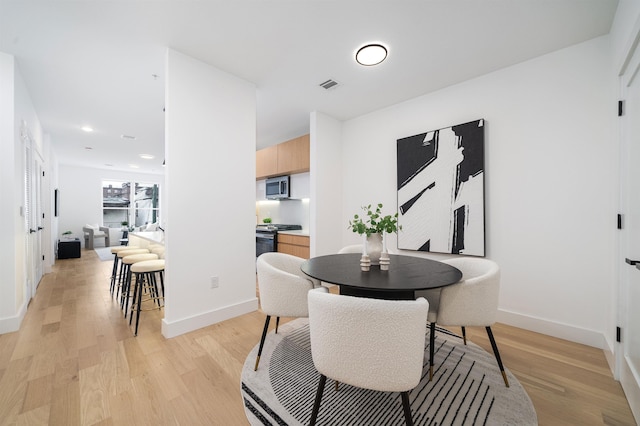 dining space featuring light wood-type flooring, visible vents, baseboards, and recessed lighting