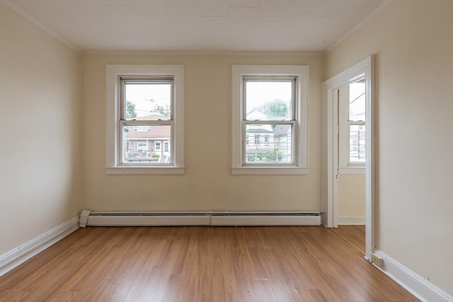 empty room with a baseboard heating unit, crown molding, and plenty of natural light