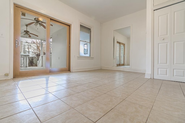 empty room featuring a ceiling fan, baseboards, and light tile patterned floors