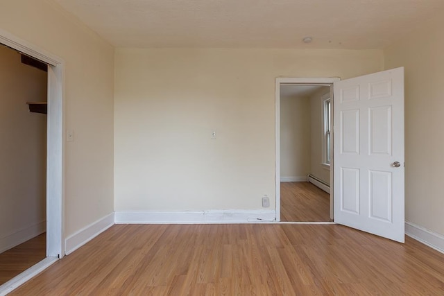 unfurnished bedroom featuring baseboards, light wood finished floors, and baseboard heating