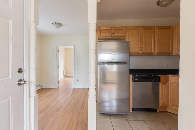 kitchen with dark countertops, light wood-style floors, baseboards, a baseboard radiator, and appliances with stainless steel finishes