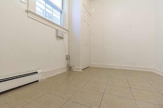 interior space featuring a baseboard radiator, baseboards, and light tile patterned flooring