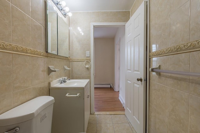 bathroom featuring a baseboard heating unit, vanity, tile walls, toilet, and tile patterned flooring