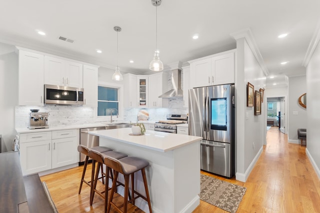 1163 Summit Ave Unit 1, Jersey City, NJ 07307 - kitchen with stainless steel appliances, wall chimney range hood, crown molding, white cabinets, and backsplash