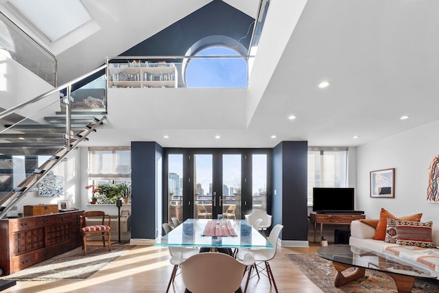 interior space with a skylight, a high ceiling, wood finished floors, and recessed lighting