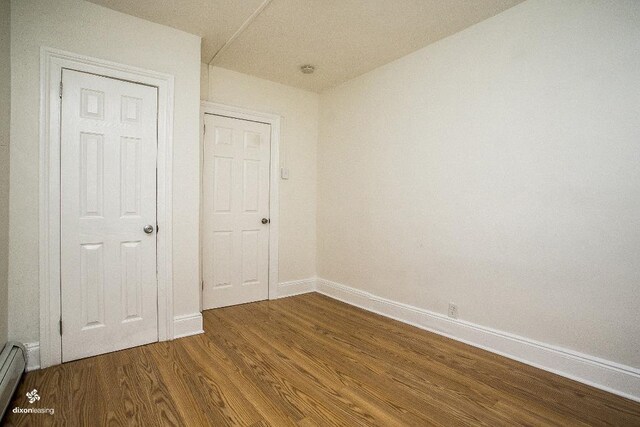 1043 Broadway, Bayonne, NJ 07002 - unfurnished bedroom with wood finished floors, baseboards, and a baseboard heating unit