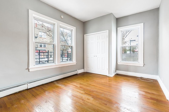 1043 Broadway, Bayonne, NJ 07002 - unfurnished bedroom with a baseboard radiator, wood finished floors, baseboards, and a closet