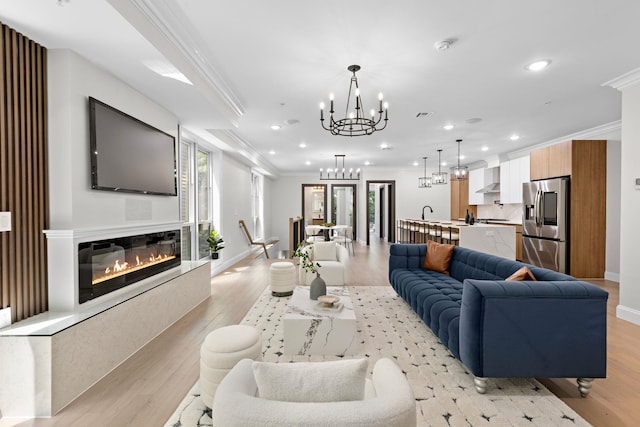 living room with light hardwood / wood-style floors, crown molding, and an inviting chandelier