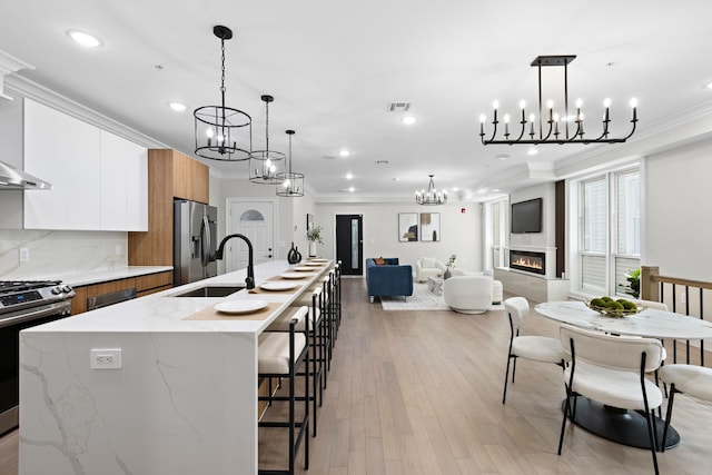 kitchen featuring appliances with stainless steel finishes, sink, white cabinets, light hardwood / wood-style floors, and an island with sink